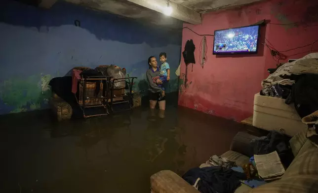 Patricia Pescarolo holds her son Gael inside their flooded home in the Jardim Pantanal neighborhood of Sao Paulo after heavy rains, Monday, Feb. 3, 2025. (AP Photo/Andre Penner)