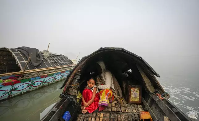 A minor girl sits with her grandmother on a boat in the river Brahmaputra as she awaits her father's return from a fish market in Guwahati, India, Wednesday, Feb. 5, 2025. (AP Photo/Anupam Nath)