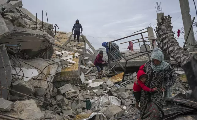 Fatima Rehan carries her 2-year-old son Mohammed as she and other members of the Rehan family search amid the rubble of their home destroyed by the Israeli army's air and ground offensive against Hamas in Jabaliya, Gaza Strip, Wednesday, Feb. 5, 2025. (AP Photo/Abdel Kareem Hana)