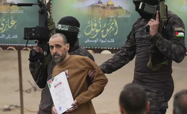 Israeli captive Eli Sharabi, who has been held hostage by Hamas in Gaza since October 7, 2023, is escorted by Hamas fighters before being handed over to the Red Cross in Deir al-Balah, central Gaza Strip, Saturday Feb. 8, 2025. (AP Photo/Abdel Kareem Hana)