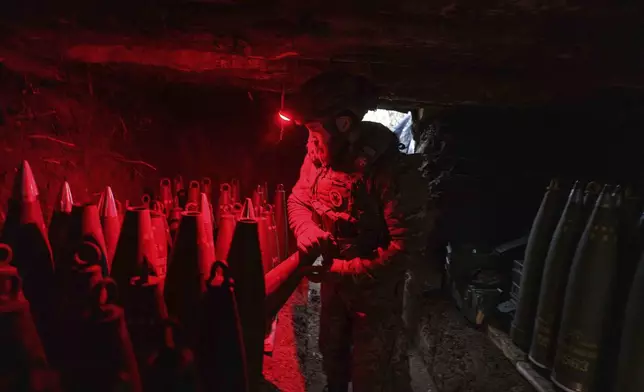 A Ukrainian serviceman of the 148th artillery brigade prepares 155mm artillery shells for a M777 howitzer before firing towards Russian positions at the frontline on Velyka Novosilka direction, Donetsk region, Ukraine, Jan. 26, 2025. (AP Photo/Evgeniy Maloletka)