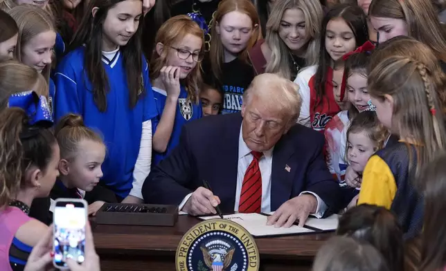 President Donald Trump signs an executive order barring transgender female athletes from competing in women's or girls' sporting events, in the East Room of the White House, Wednesday, Feb. 5, 2025, in Washington. (AP Photo/Alex Brandon)