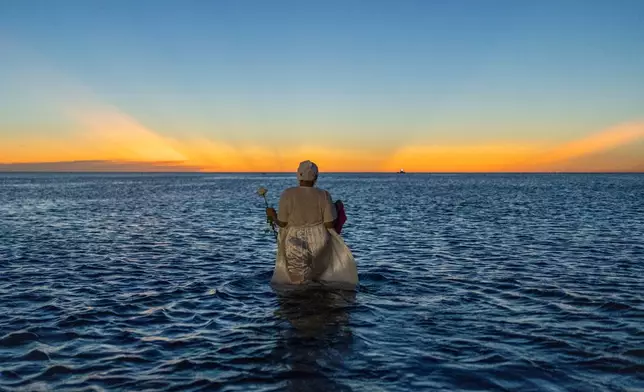 A woman wades into the waters of Ramirez Beach as part of a ritual honoring the African sea goddess Yemanja, in Montevideo, Uruguay, Sunday, Feb. 2, 2025. (AP Photo/Matilde Campodonico)