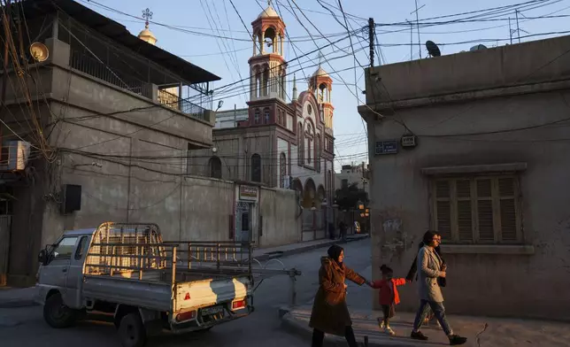 Muslim women walk past the Syriac Orthodox Church of the Virgin Mary in the northeastern Syrian city of Qamishli, which is controlled by the U.S.-backed, Kurdish-led Syrian Democratic Forces, Tuesday, Jan. 28, 2025. (AP Photo/Bernat Armangue)