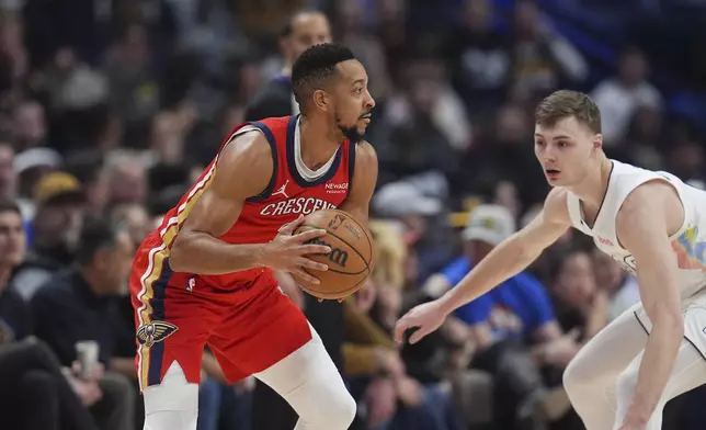 New Orleans Pelicans guard CJ McCollum, left, looks to pass the ball as Denver Nuggets guard Christian Braun defends in the first half of an NBA basketball game, Wednesday, Feb. 5, 2025, in Denver. (AP Photo/David Zalubowski)