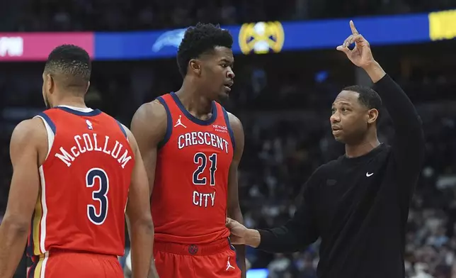 New Orleans Pelicans head coach Willie Green, right, confers with center Yves Missi as guard CJ McCollum heads back to play in the first half of an NBA basketball game against the Denver Nuggets Wednesday, Feb. 5, 2025, in Denver. (AP Photo/David Zalubowski)