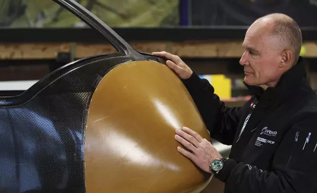 Swiss aviation pioneer Bertrand Piccard touches Climate Impulse, a plane powered by liquid hydrogen, at the press presentation of the project in a hangar in Les Sables d'Olonne, France, Thursday, Feb. 13, 2025. (AP Photo/Yohan Bonnet)