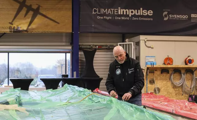 Raphael Dinelli, Climate Impulse engineer and co-pilot, stands near wings of the plane, powered by liquid hydrogen, at a press presentation of the project in a hangar in Les Sables d'Olonne, France on Thursday, Feb. 13, 2025.(AP Photo/Yohan Bonnet)