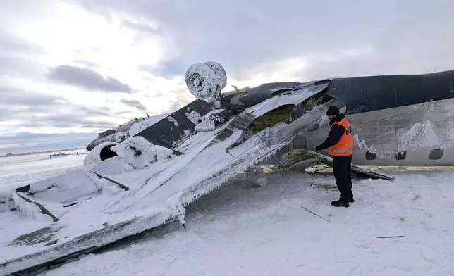 CORRECTS SOURCE TO TRANSPORTATION SAFETY BOARD OF CANADA INSTEAD OF NATIONAL TRANSPORTATION SAFETY BOARD - In this image provided by the Transportation Safety Board of Canada, an investigator examines the wreckage of a Delta Air Lines jet, Wednesday, Feb. 19, 2025, that burst into flames and flipped upside down as it tried to land on Feb. 17, at Toronto Pearson International Airport in Mississauga, Ontario. (Transportation Safety Board of Canada via AP)