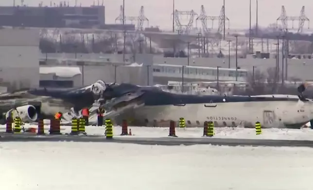 This image taken from video provided by CTV shows workers near the crashed passenger jet on a tarmac of the Toronto Pearson Airport on Wednesday, Feb.19, 2025. (CTV via AP)