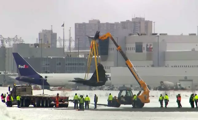This image taken from video provided by CTV shows a crane lifting debris of a plane at Toronto Pearson Airport on Wednesday, Feb.19, 2025. (CTV via AP)