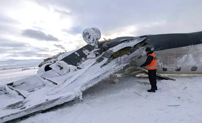 In this image provided by the National Transportation Safety Board, an investigator examines the wreckage of a Delta Air Lines jet, Wednesday, Feb. 19, 2025, that burst into flames and flipped upside down as it tried to land on Feb. 17, at Toronto Pearson International Airport in Mississauga, Ontario. (National Transportation Safety Board via AP)