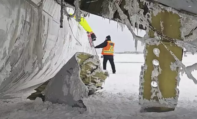 In this image provided by the National Transportation Safety Board, investigators examine the wreckage of a Delta Air Lines jet, Wednesday, Feb. 19, 2025, that burst into flames and flipped upside down as it tried to land on Feb. 17, at Toronto Pearson International Airport in Mississauga, Ontario. (National Transportation Safety Board via AP)