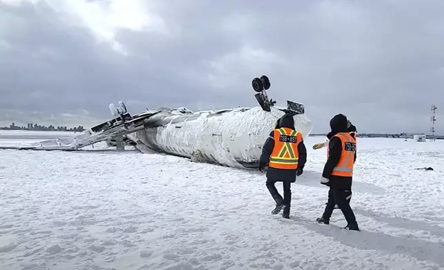 In this image provided by the National Transportation Safety Board, investigators examine the wreckage of a Delta Air Lines jet, Wednesday, Feb. 19, 2025, that burst into flames and flipped upside down as it tried to land on Feb. 17, at Toronto Pearson International Airport in Mississauga, Ontario. (National Transportation Safety Board via AP)