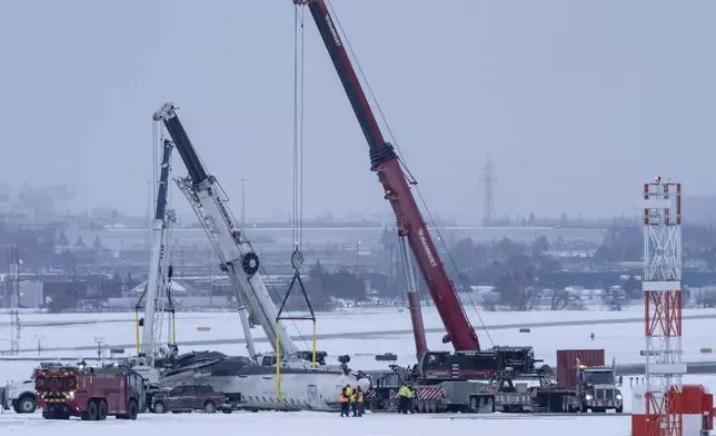 Cranes are positioned to remove the wreckage of Delta Flight 4819 from the runway at Toronto Pearson International Airport, in Mississauga, Ontario, on Wednesday, Feb. 19, 2025. (Arlyn McAdorey/The Canadian Press via AP)