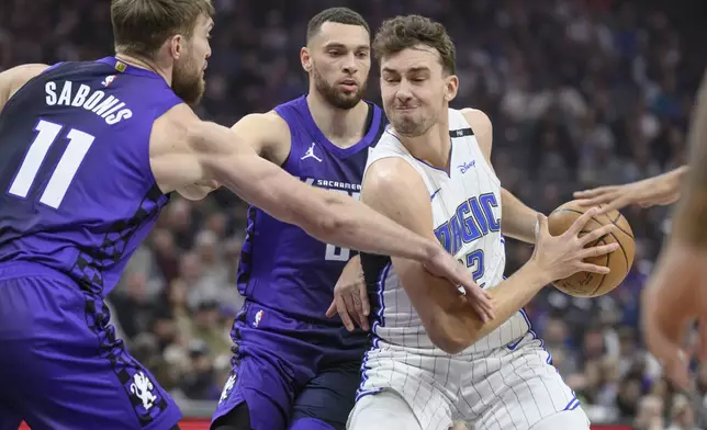 Orlando Magic forward Franz Wagner, right, is guarded by Sacramento Kings forward Domantas Sabonis (11) and Zach LaVine during the first half of an NBA basketball game in Sacramento, Calif., Wednesday, Feb. 5, 2025. (AP Photo/Randall Benton)