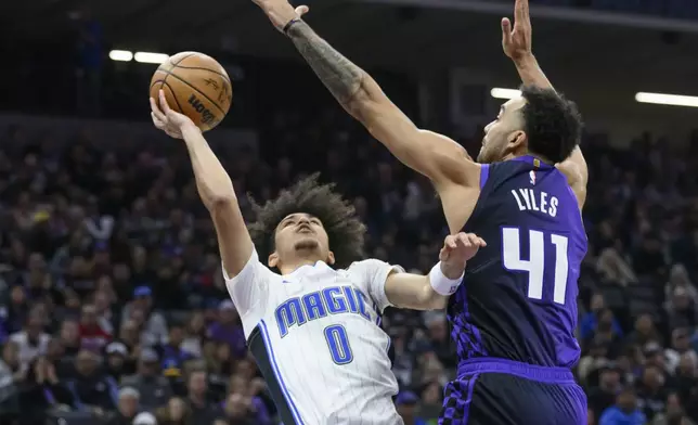 Orlando Magic guard Anthony Black (0) shoots over Sacramento Kings forward Trey Lyles (41) during the first half of an NBA basketball game in Sacramento, Calif., Wednesday, Feb. 5, 2025. (AP Photo/Randall Benton)