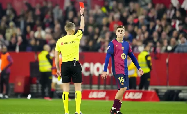 Referee Alejandro Jose Hernandez Hernandez a red card to Barcelona's Fermin Lopez during a Spanish La Liga soccer match between Sevilla and FC Barcelona at the Ramon Sanchez Pizjuan stadium in Seville, Spain, Sunday, Feb. 9, 2025. (AP Photo/Jose Breton)