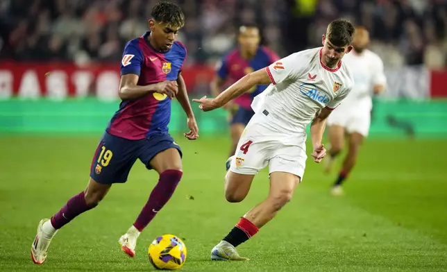Barcelona's Lamine Yamal, left, vies for the ball with Sevilla's Kike Salas during a Spanish La Liga soccer match between Sevilla and FC Barcelona at the Ramon Sanchez Pizjuan stadium in Seville, Spain, Sunday, Feb. 9, 2025. (AP Photo/Jose Breton)