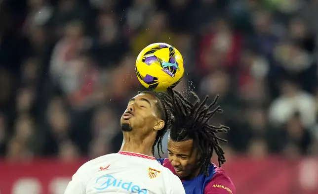 Sevilla's Loic Bade jumps for the ball with Barcelona's Jules Kounde, right, during a Spanish La Liga soccer match between Sevilla and FC Barcelona at the Ramon Sanchez Pizjuan stadium in Seville, Spain, Sunday, Feb. 9, 2025. (AP Photo/Jose Breton)