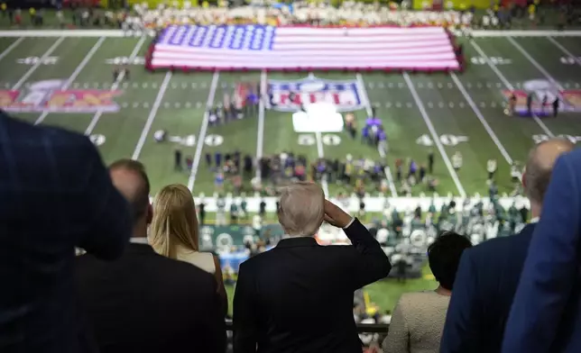 President Donald Trump, center, salutes as Jon Batiste performs the national anthem at the NFL Super Bowl 59 football game between the Philadelphia Eagles and the Kansas City Chiefs, Sunday, Feb. 9, 2025, in New Orleans. (AP Photo/Ben Curtis)