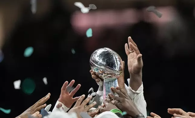 Members of the Philadelphia Eagles celebrate with the Vince Lombardi Trophy after defeating the Kansas City Chiefs in NFL Super Bowl 59 football game, Sunday, Feb. 9, 2025, in New Orleans. (AP Photo/Doug Benc)