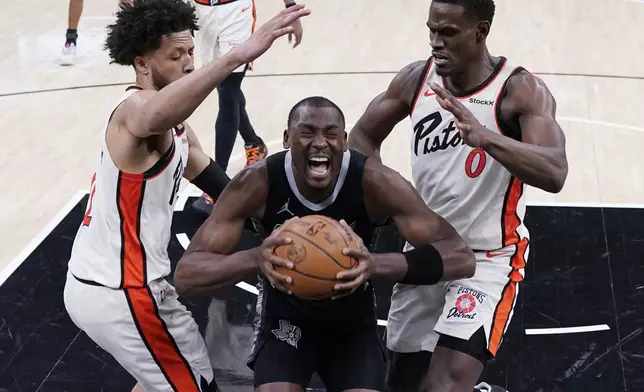 San Antonio Spurs center Bismack Biyombo, center, is pressured by Detroit Pistons center Jalen Duren (0) and guard Cade Cunningham, left, during the second half of an NBA basketball game in Austin, Texas, Friday, Feb. 21, 2025. (AP Photo/Eric Gay)