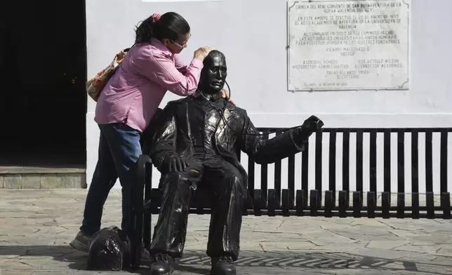 A woman embraces a statue of José Gregorio Hernandez, the physician known as the "doctor of the poor", in Valencia, Venezuela, Tuesday, Feb. 25, 2025. Pope Francis on Tuesday approved a decree to canonize Hernandez, making him Venezuela's first saint. (AP Photo/Jacinto Oliveros)
