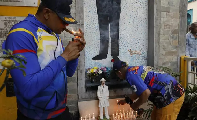 Devotees of folklore spiritual deity Maria Lionza visit the memorial dedicated to Dr. Jose Gregorio Hernandez, on the street where he died when hit by a car in 1919, in La Pastora neighborhood of Caracas, Venezuela, Tuesday, Feb. 25, 2025, after Pope Francis approved the canonization of the physician as Venezuela's first saint. (AP Photo/Cristian Hernandez)