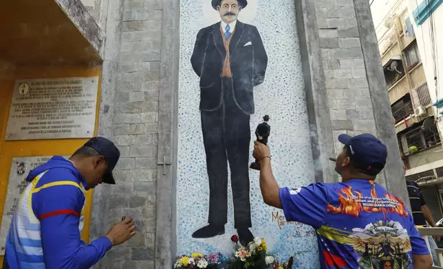 Devotees of folklore spiritual deity Maria Lionza smoke cigars in front the memorial dedicated to Dr. Jose Gregorio Hernandez, on the street where he died when hit by a car in 1919, in La Pastora neighborhood of Caracas, Venezuela, Tuesday, Feb. 25, 2025, after Pope Francis approved the canonization of the physician as Venezuela's first saint. (AP Photo/Cristian Hernandez)