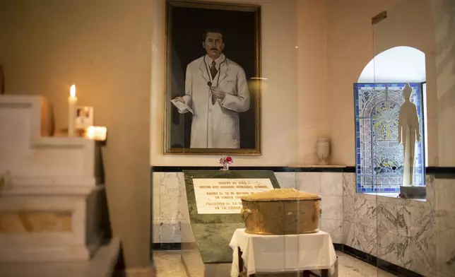 FILE - The remains of Dr. Jose Gregorio Hernandez, popularly known as the "doctor of the poor", are displayed in an urn backdropped by his portrait, inside the La Candelaria Catholic church, in Caracas, Venezuela, April 23, 2021. (AP Photo/Ariana Cubillos, File)