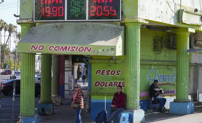 People wait for ground transportation near an exchange office in Mexicali, Mexico, Saturday, Feb. 1, 2025. (AP Photo/Fernando Llano)