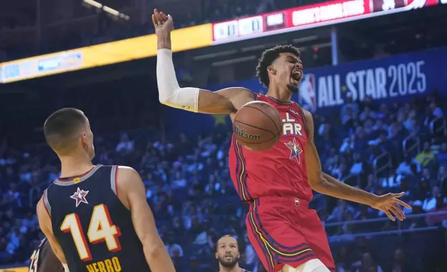 San Antonio Spurs center Victor Wembanyama dunks past Miami Heat guard Tyler Herro during the NBA All-Star basketball game Sunday, Feb. 16, 2025, in San Francisco. (AP Photo/Godofredo A. Vásquez)
