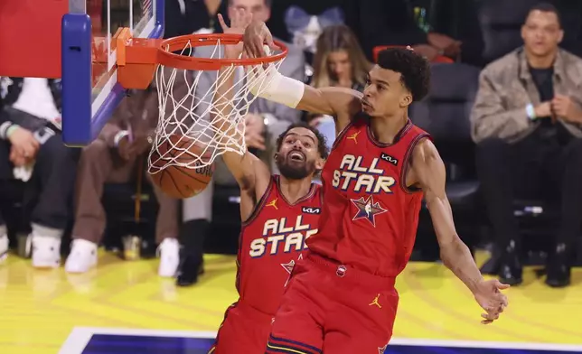 San Antonio Spurs center Victor Wembanyama dunks past teammate Trae Young during the NBA All-Star basketball game Sunday, Feb. 16, 2025, in San Francisco. (AP Photo/Jed Jacobsohn)