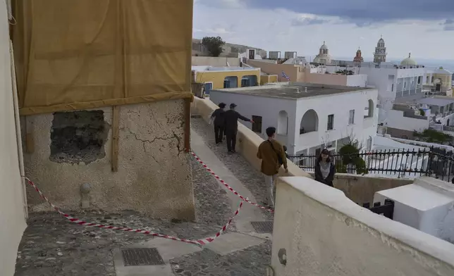 Tourists walk on the narrow streets of Fira town as emergency crews were deployed after an earthquake swarm worries Greek experts on the popular Aegean Sea holiday island of Santorini, southern Greece, Monday, Feb. 3, 2025. (AP Photo/Petros Giannakouris)