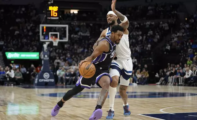 Sacramento Kings guard Malik Monk, left, works toward the basket as Minnesota Timberwolves guard Nickeil Alexander-Walker defends during the first half of an NBA basketball game Monday, Feb. 3, 2025, in Minneapolis. (AP Photo/Abbie Parr)