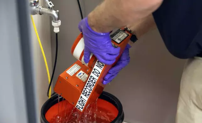 In this image provided by the National Transportation Safety Board, NTSB investigators examine the flight data recorder in Washington, Thursday, Jan. 30, 2025, recovered from the American Airlines passenger jet that crashed with an Army helicopter Wednesday night near Ronald Reagan Washington National Airport. (NTSB via AP)
