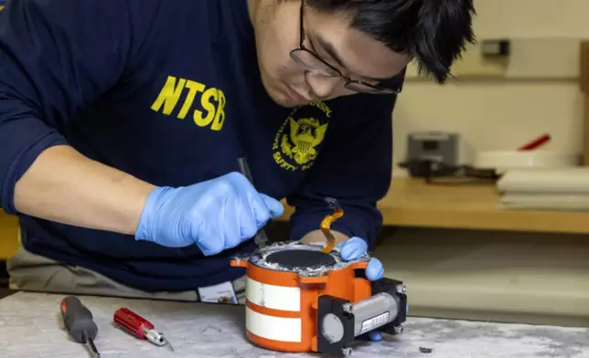 In this image provided by the National Transportation Safety Board, a NTSB investigator examine cockpit voice recorder and flight data recorder in Washington, Thursday, Jan. 30, 2025, recovered from the American Airlines passenger jet that crashed with an Army helicopter Wednesday night near Ronald Reagan Washington National Airport. (NTSB via AP)