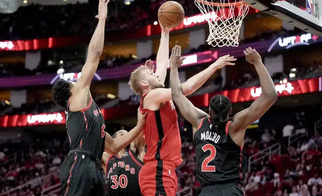 Houston Rockets center Jock Landale, center front, shoots as Toronto Raptors forward Scottie Barnes, left, and forward Jonathan Mogbo (2) defend during the first half of an NBA basketball game Sunday, Feb. 9, 2025, in Houston. (AP Photo/Eric Christian Smith)