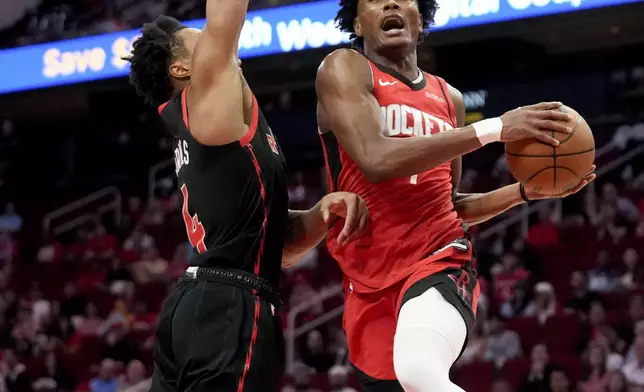 Houston Rockets forward Amen Thompson, right, drives to the basket as Toronto Raptors forward Scottie Barnes (4) defends during the first half of an NBA basketball game Sunday, Feb. 9, 2025, in Houston. (AP Photo/Eric Christian Smith)