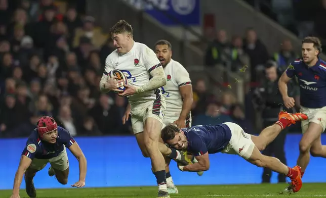 England's Tommy Freeman, center, breaks the tackle of France's Antoine Dupont to score a try during the Six Nations rugby union match between England and France at Twickenham in London, Saturday, Feb. 8, 2025. (AP Photo/Ian Walton)