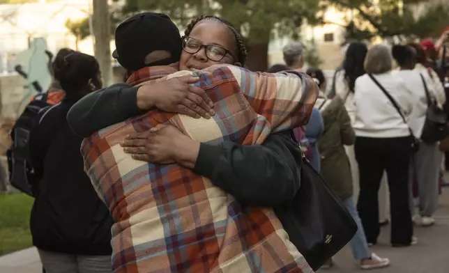 People impacted by the Eaton Fire take each other in their arms as they wait in line to access Pasadena City College's gymnasium where The Change Reaction will be handing out about 1,000 checks of between $2,500-$5,000, Tuesday, Jan. 28, 2025 in Pasadena, Calif. (AP Photo/Etienne Laurent)