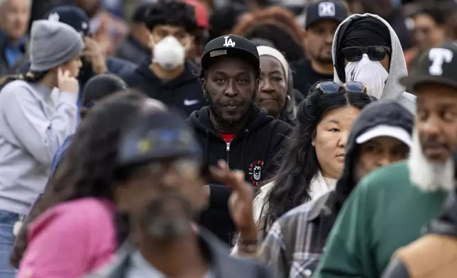 People impacted by the Eaton Fire wait in line to access Pasadena City College's gymnasium, where The Change Reaction will be handing out about 1,000 checks of between $2,500-$5,000, Tuesday, Jan. 28, 2025 in Pasadena, Calif. (AP Photo/Etienne Laurent)