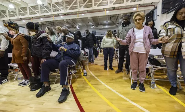 People impacted by the Eaton Fire pray as they attend an event at the gymnasium of Pasadena City College where The Change Reaction will be handing out about 1,000 checks of between $2,500-$5,000, Tuesday, Jan. 28, 2025 in Pasadena, Calif. (AP Photo/Etienne Laurent)
