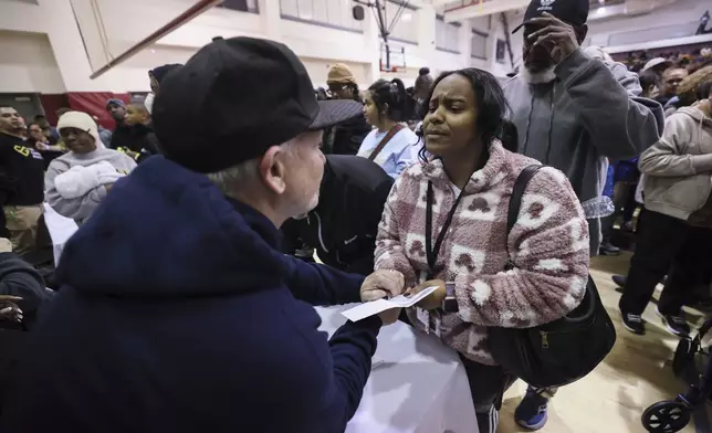 A woman reacts as she receives a check at the gymnasium of Pasadena City College where The Change Reaction is handing out about 1,000 checks of between $2,500-$5,000, Tuesday, Jan. 28, 2025 in Pasadena, Calif. (AP Photo/Etienne Laurent)