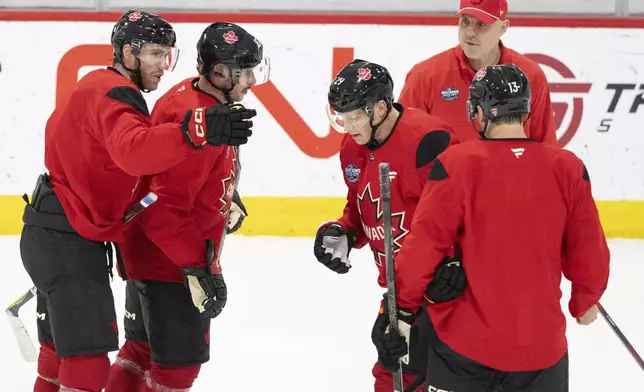 Canada's Connor McDavid, left, speaks with Sidney Crosby, second from left, as they work drills with teammates Nathan MacKinnon, third from left, and Sam Reinhart (13) during a 4 Nations Face-Off hockey practice in Brossard, Quebec, Monday, Feb. 10, 2025. (Christinne Muschi/The Canadian Press via AP)