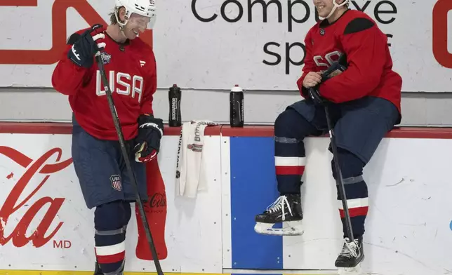 U.S. players Jake Sanderson, left and Brock Faber talk during a 4 Nations Face-Off hockey practice in Brossard, Que., on Monday, Feb. 10, 2025. (Christinne Muschi/The Canadian Press via AP)