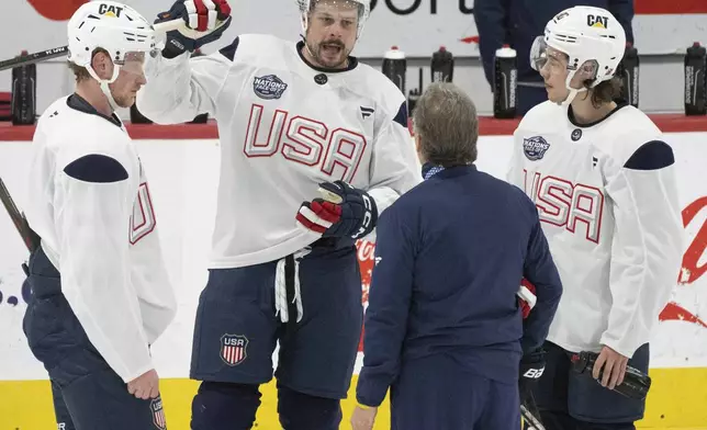 United States' Austin Matthews, second from left, Jack Eichel, left, and Jack Hughes, right, speak with coaching staff during during a 4 Nations Face-Off hockey practice in Brossard, Quebec, Monday, Feb. 10, 2025. (Christinne Muschi/The Canadian Press via AP)