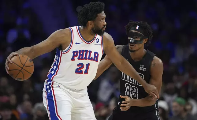 Philadelphia 76ers' Joel Embiid, left, tries to get past Brooklyn Nets' Nic Claxton during the first half of an NBA basketball game, Saturday, Feb. 22, 2025, in Philadelphia. (AP Photo/Matt Slocum)