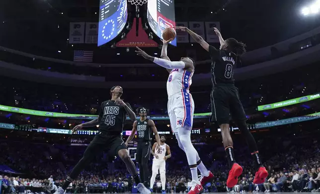 Philadelphia 76ers' Paul George, center, goes up for a shot against Brooklyn Nets' Ziaire Williams during the first half of an NBA basketball game, Saturday, Feb. 22, 2025, in Philadelphia. (AP Photo/Matt Slocum)